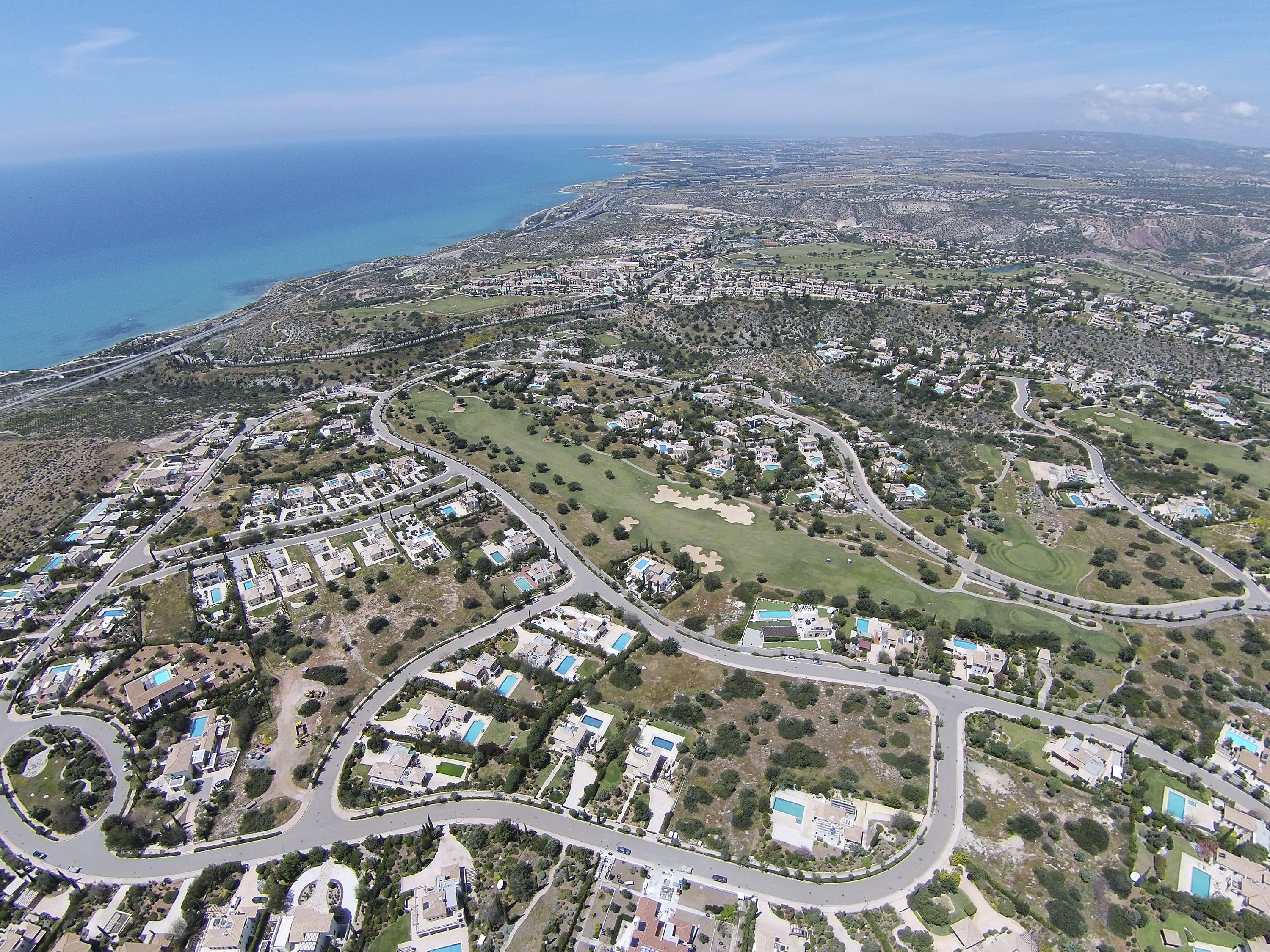 Vista aérea de una zona residencial costera con carreteras sinuosas, casas y espacios verdes.