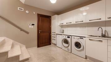 A modern kitchen with a built-in washer and dryer, a stainless steel sink, and a wooden door.