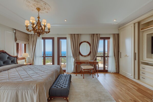 Un dormitorio amplio con una cama grande, un escritorio y vistas al mar.