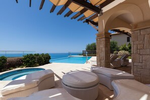 A poolside area with a view of the ocean, outdoor seating, and a pergola structure. - Aphrodite Hills Rentals – The Mythos Collection Villas (Kouklia)