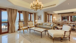 Un salón lujoso con una gran araña, muebles elegantes y vista al mar.