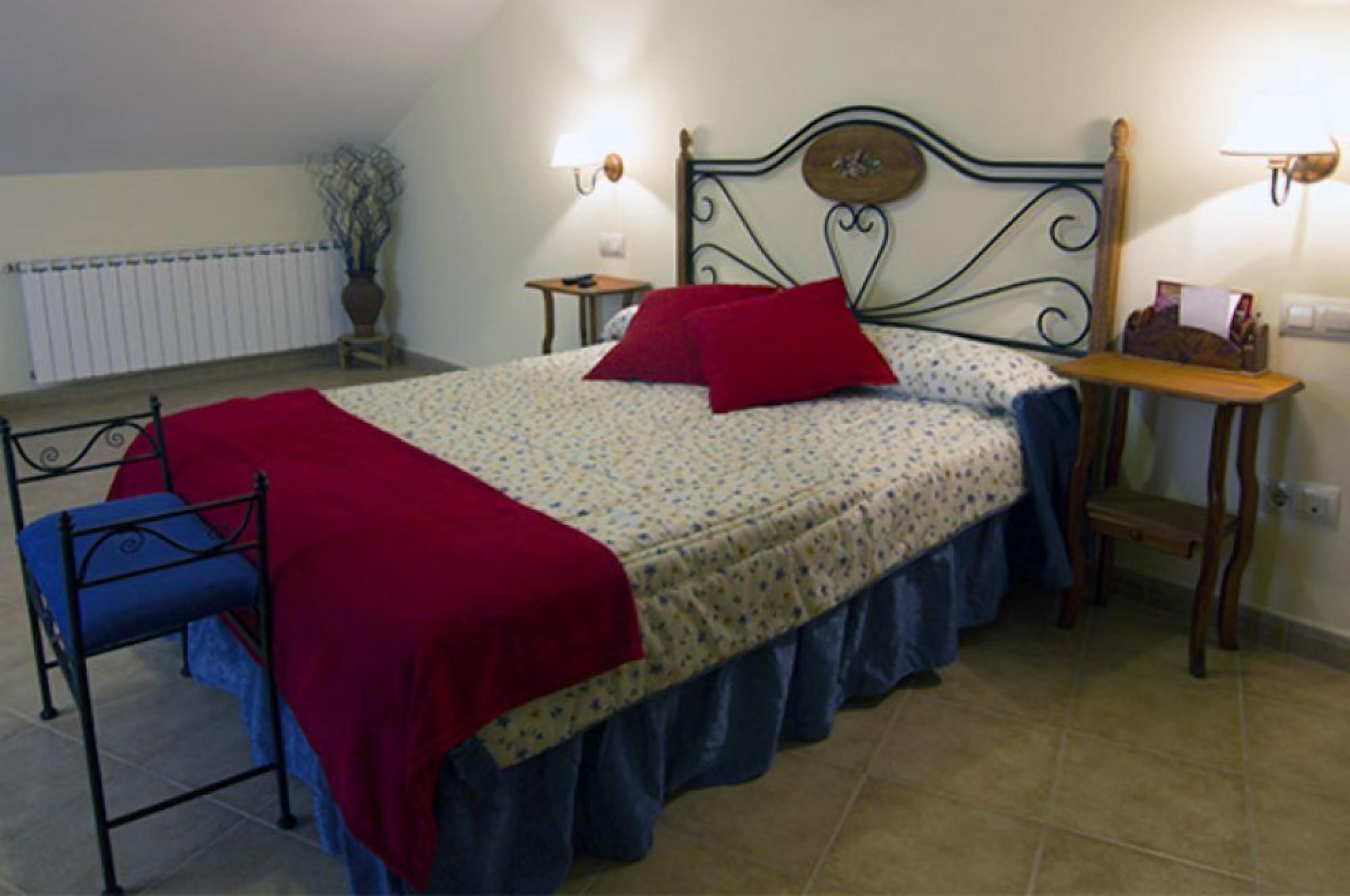 Un dormitorio con cama, una silla, una mesita de noche, una lámpara y un radiador.