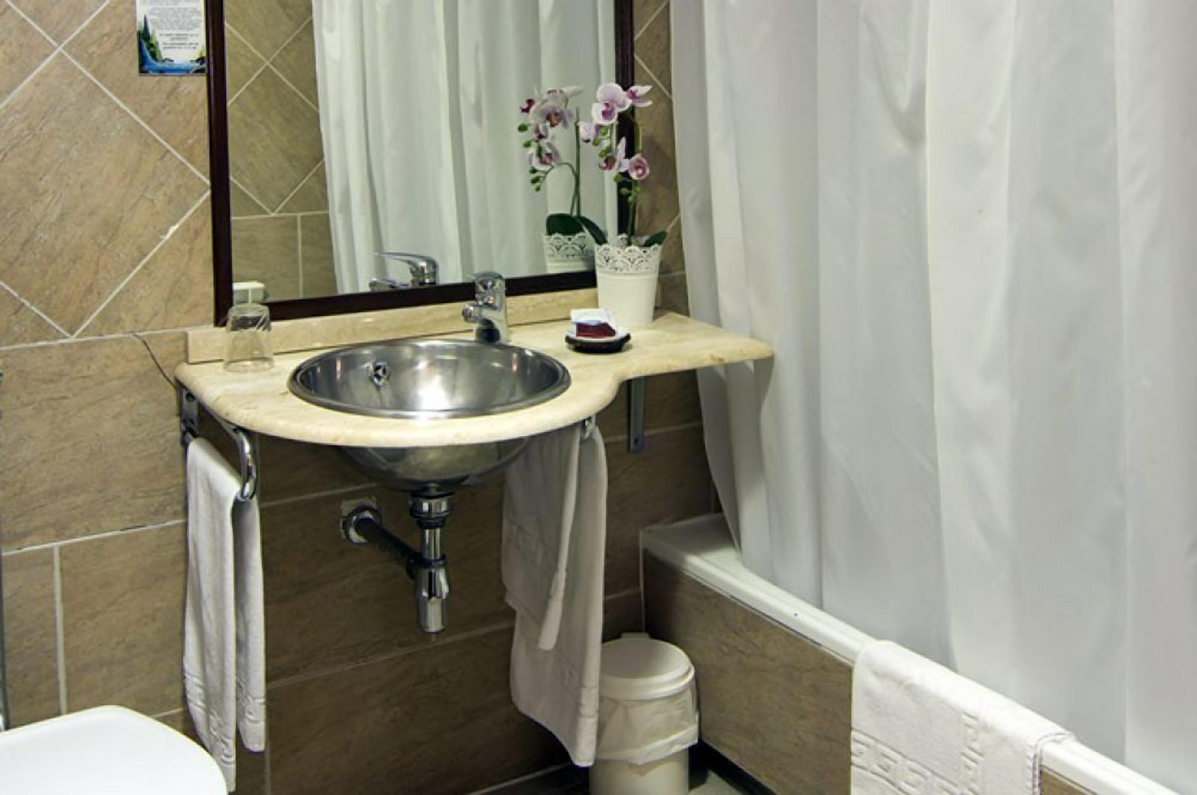 A bathroom with a sink, mirror, and potted orchid.