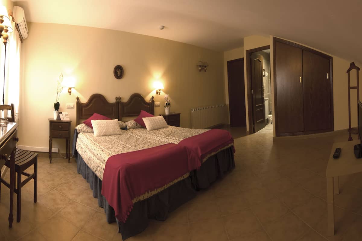 Quarto com uma cama grande, mesas de cabeceira, escrivaninha e guarda-roupa.