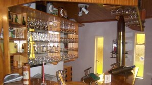 Eine Bar mit Regalen voller Gläser und Flaschen, einer Holztresen und einer Ziegelwand.