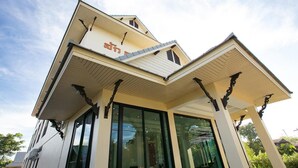 A modern building with a sloped roof, large windows, and a prominent entrance with decorative elements. - SakSukSmile Resort (Sukhothai)