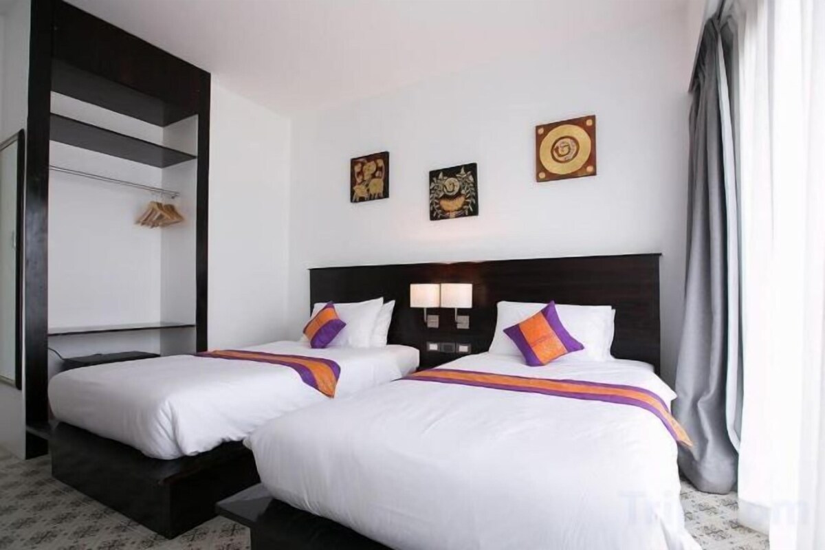 A hotel room with two beds, a dark headboard, and a small seating area.