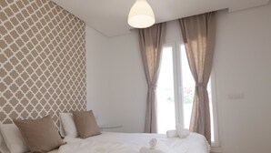 A modern bedroom with a bed, pillows, and a bedside table.
