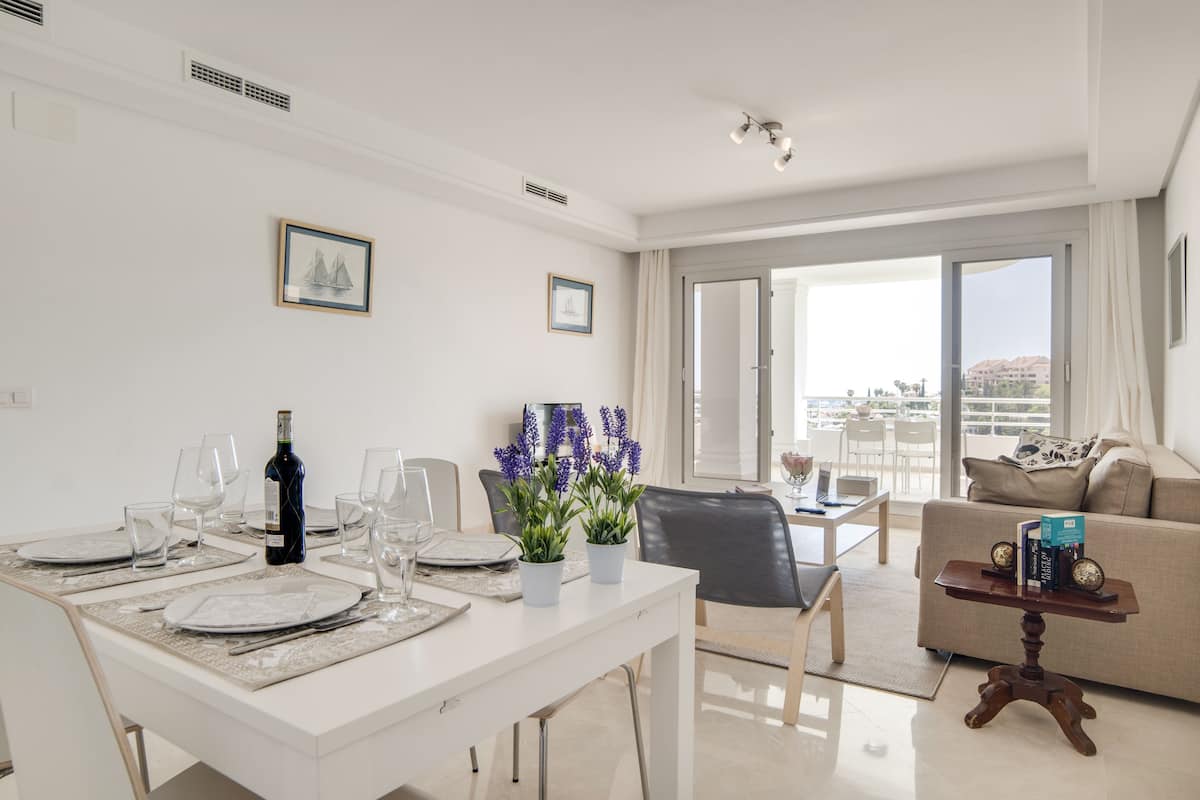 Una sala de estar moderna con comedor, que incluye un sofá, una mesa de centro y una mesa de comedor para dos.