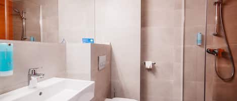 Un baño moderno con un lavabo blanco, un inodoro y una zona de ducha con mampara de vidrio.