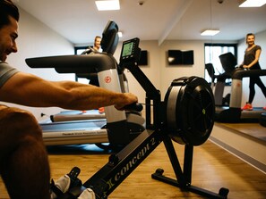 Un gimnasio con equipo de ejercicio, incluyendo una máquina de remo y cintas de correr.