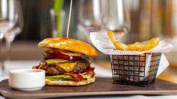 A burger and fries on a wooden board with a small cup of sauce.