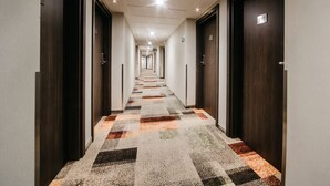 A hotel hallway with carpeted floors, wooden doors, and a ceiling with recessed lighting. - Q Hotel Plus Katowice (Katowice)