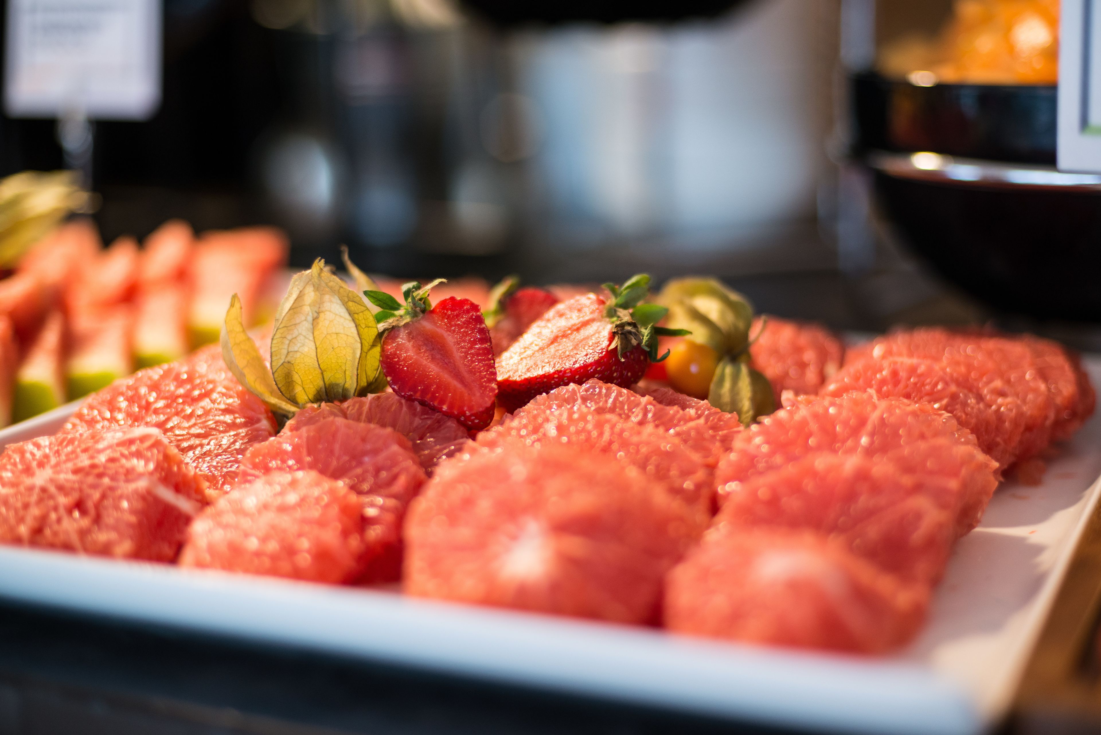A plate of raw fish and sliced strawberries.