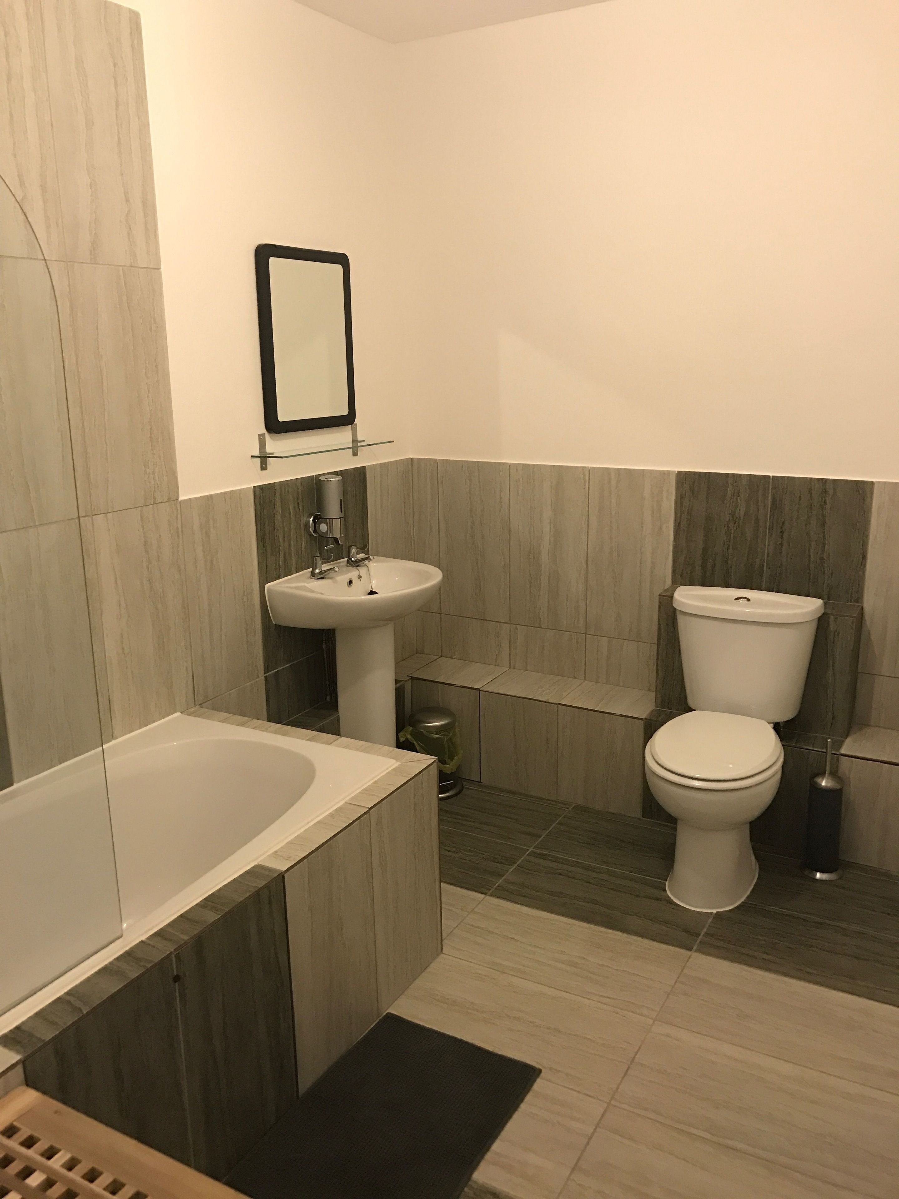A modern bathroom with a bathtub, sink, and toilet.