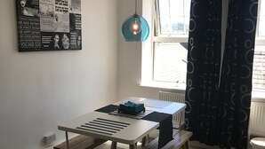 Un espace repas comprenant une table et des bancs, un luminaire suspendu, une fenêtre avec des rideaux et un mur orné de citations inspirantes.