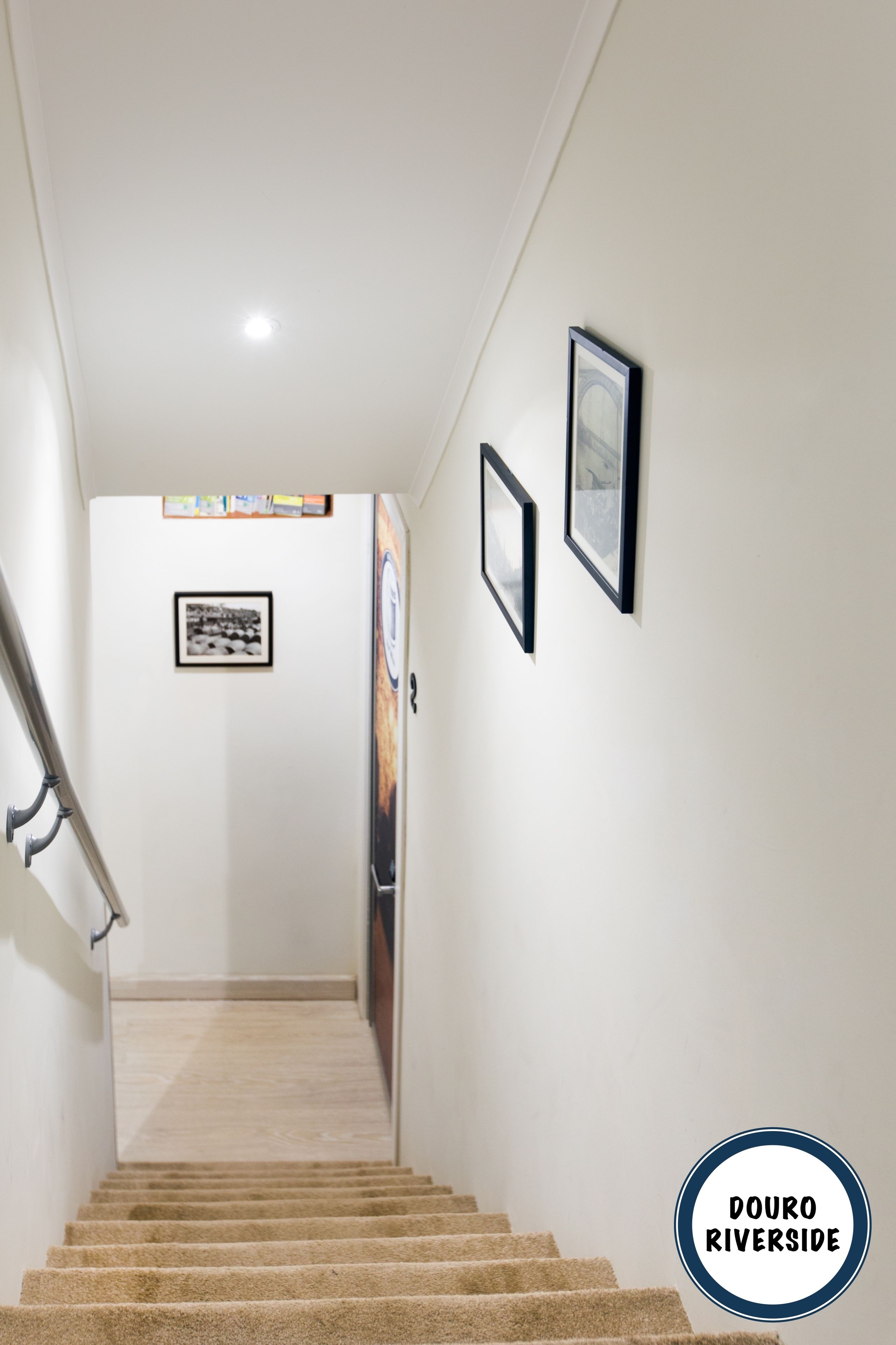 A staircase leading to a landing with framed pictures on the wall.