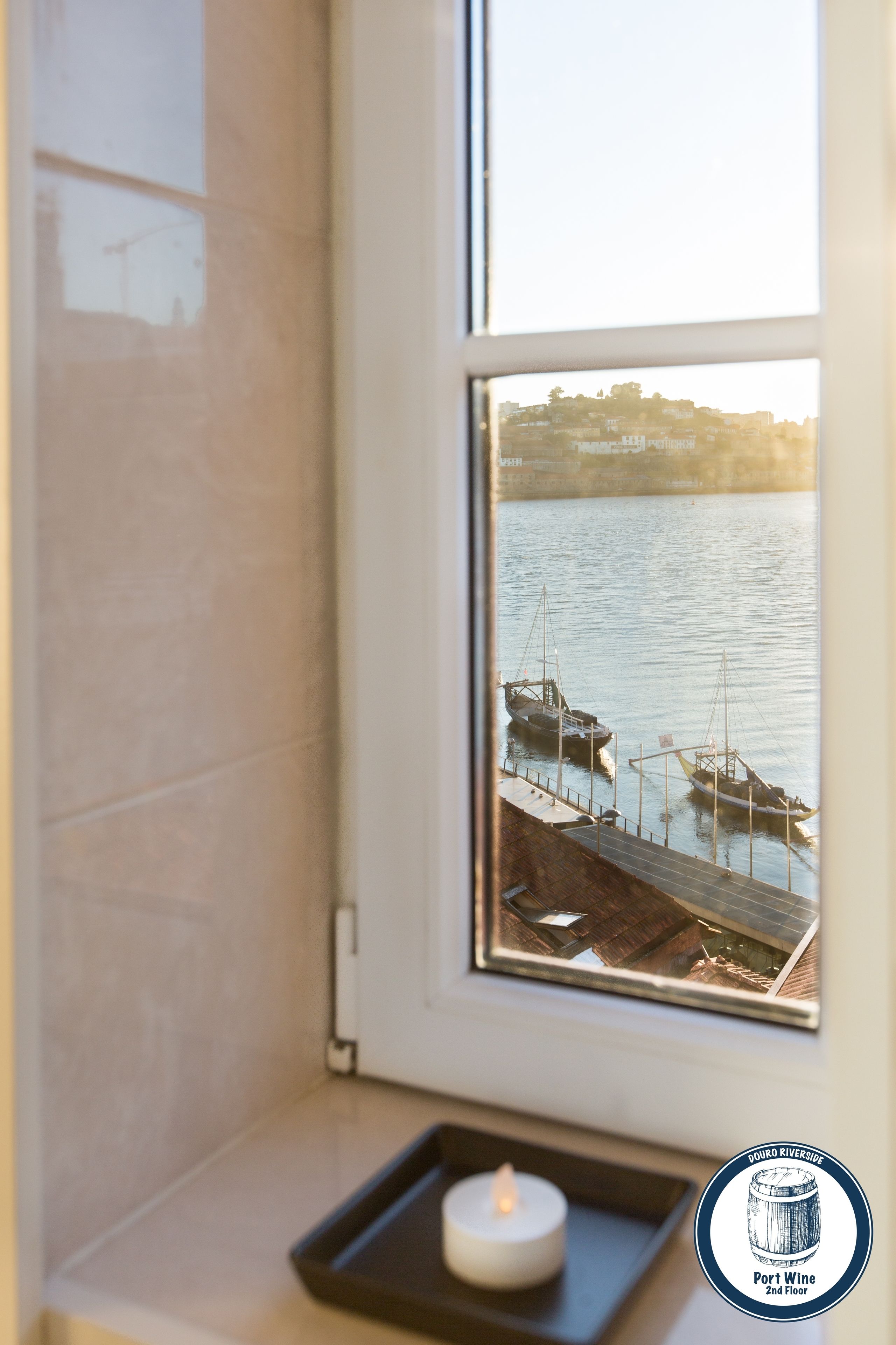 A window view of a harbor with boats, a candle on a tray, and a logo for Douro Riveride Port Wine on the 2nd floor.