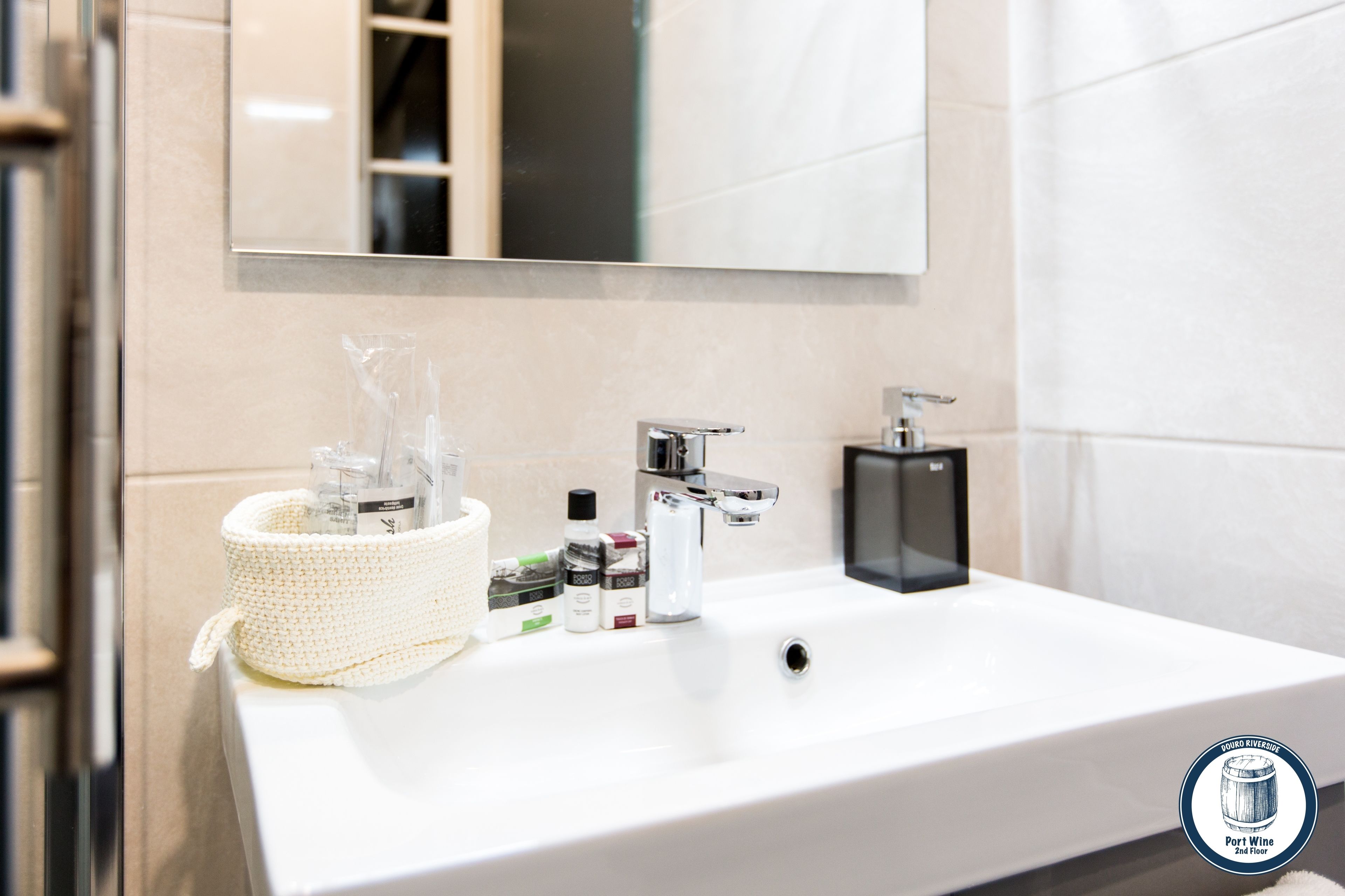 Un baño moderno con un lavamanos blanco, grifo cromado y un espejo encima.