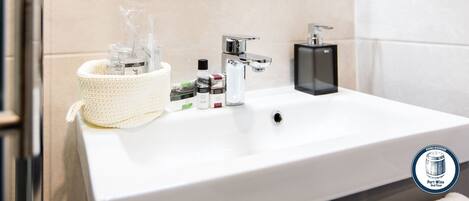 Un baño moderno con un lavamanos blanco, grifo cromado y un espejo encima.