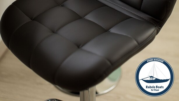 A black leather chair with a high backrest and armrests, positioned in a room with a wooden floor and a white wall. - Douro Riverside Apartments (Vila Nova de Gaia)