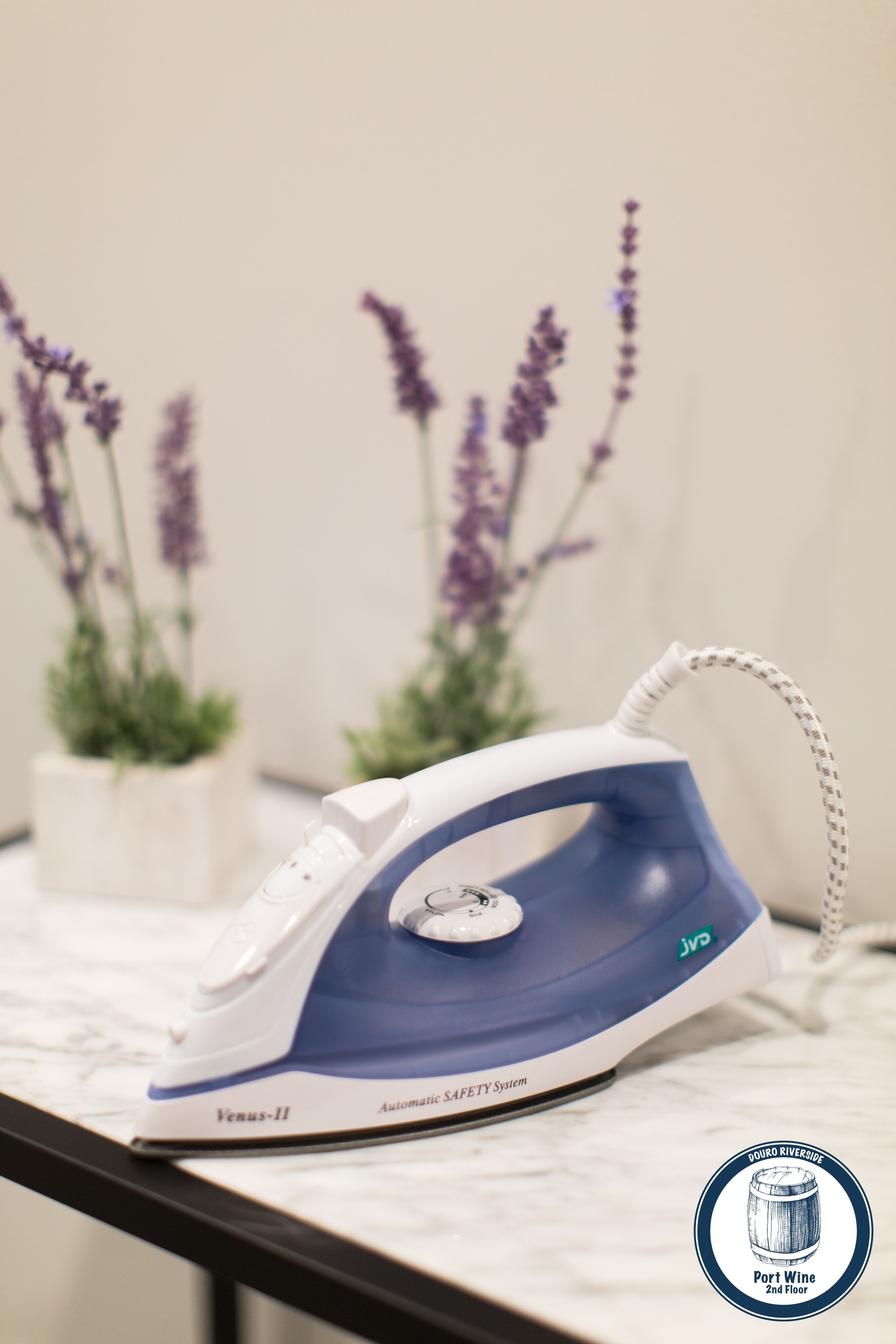An iron on a marble countertop with a white and blue design, a safety system label, and a logo.