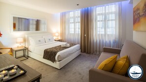 A hotel room with a bed, bedside tables, a sofa, and a large window with curtains. - Douro Riverside Apartments (Vila Nova de Gaia)