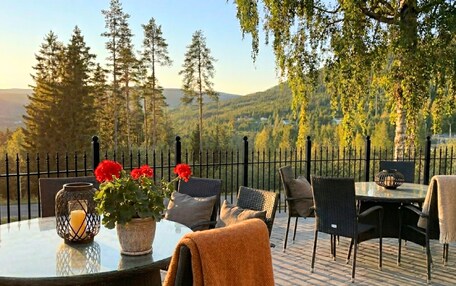 An outdoor seating area with a round table, chairs, a vase with flowers, and a candle.