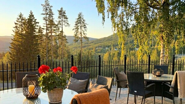 Un área de estar al aire libre con una mesa redonda, sillas, un florero con flores y una vela.