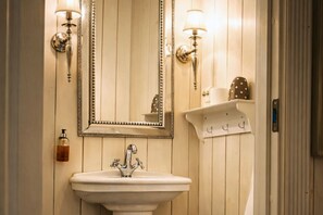 A bathroom with a white sink, two wall-mounted lights, a mirror, and a soap dispenser. - Eggedal Borgerstue (Sigdal)