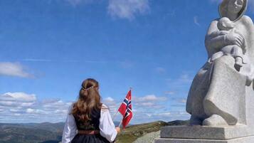 Una estatua de una mujer sosteniendo a un niño, con un cielo despejado y un paisaje montañoso al fondo.