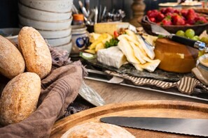 A table with various food items including bread, cheese, and fruits. - Eggedal Borgerstue (Sigdal)