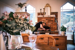 A kitchen with a brick oven, wooden furniture, and a view of the outdoors.