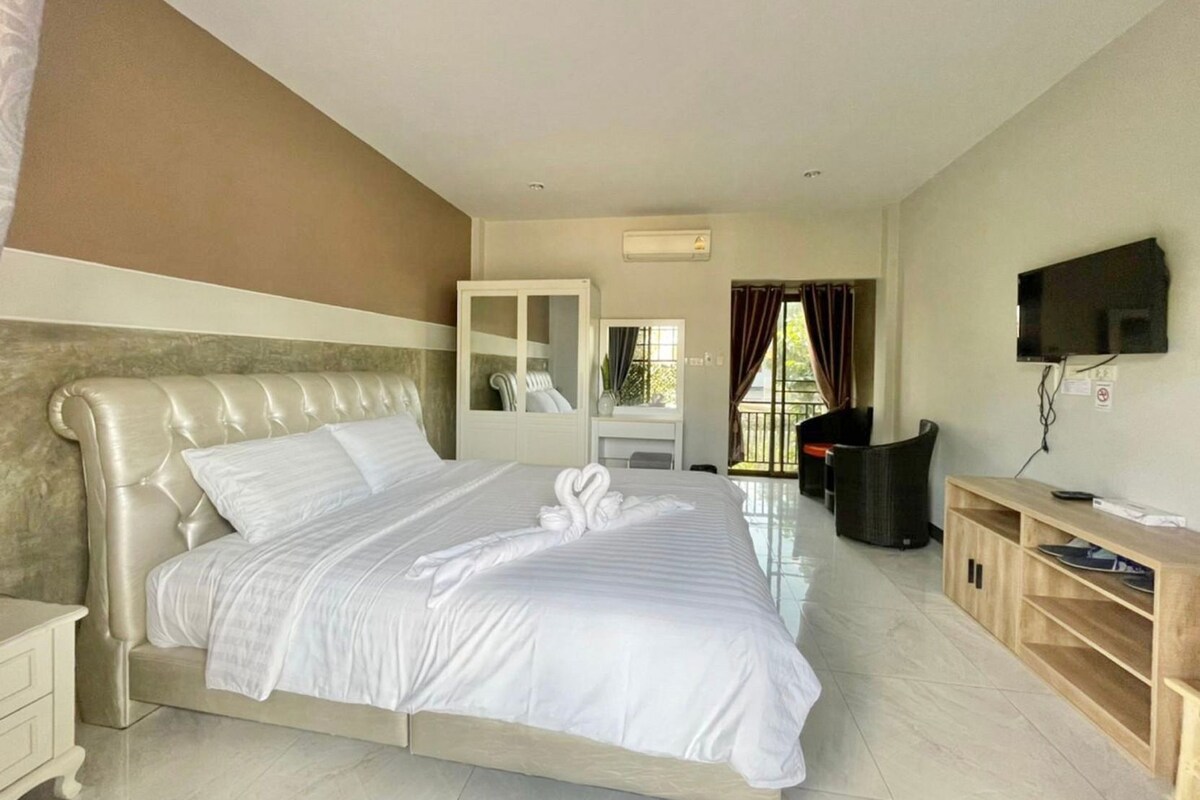 A hotel room with a large bed, a desk, a TV, and a wardrobe.