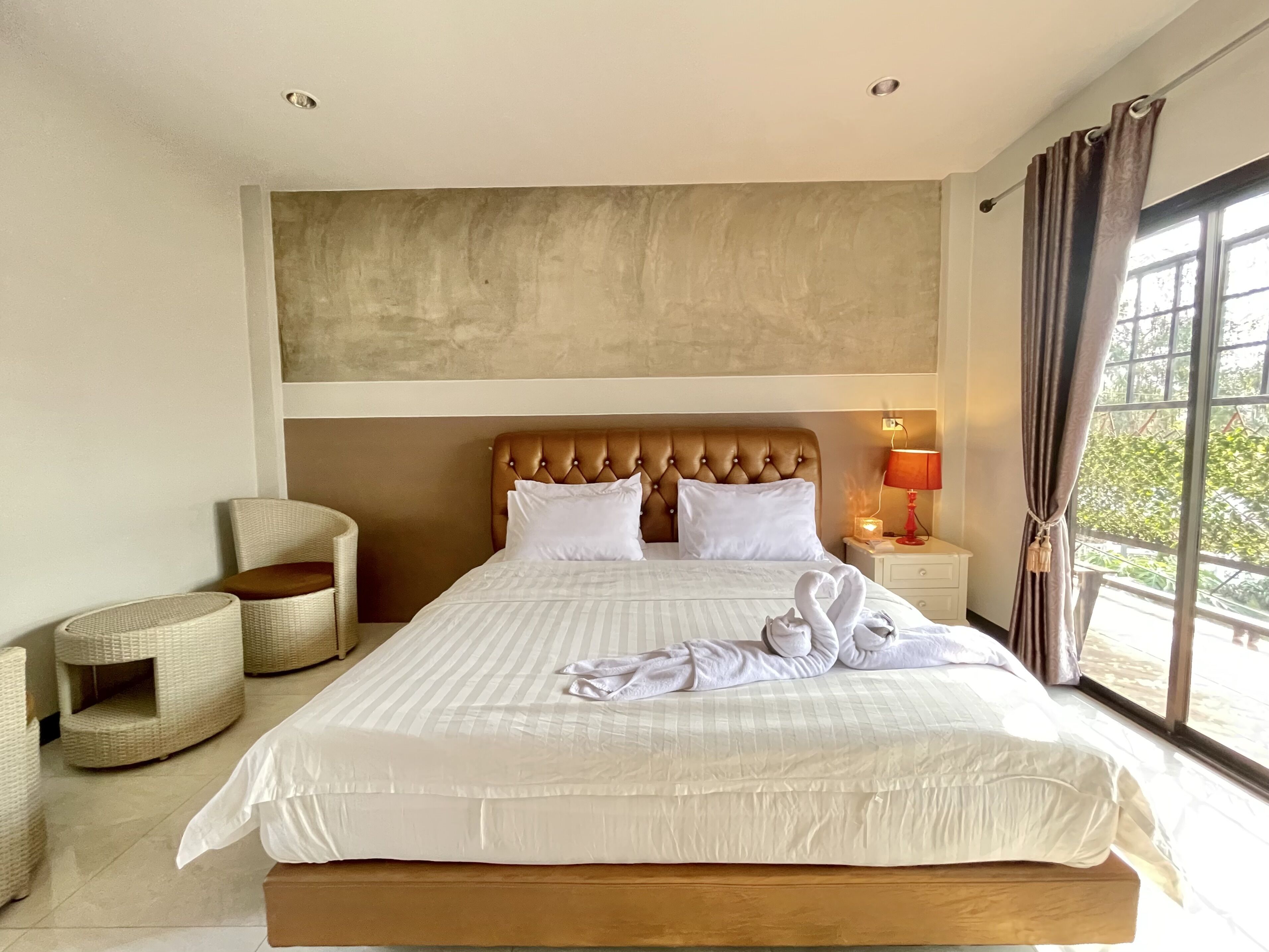 A neatly made bed with white linens, a wooden headboard, and a bedside lamp.