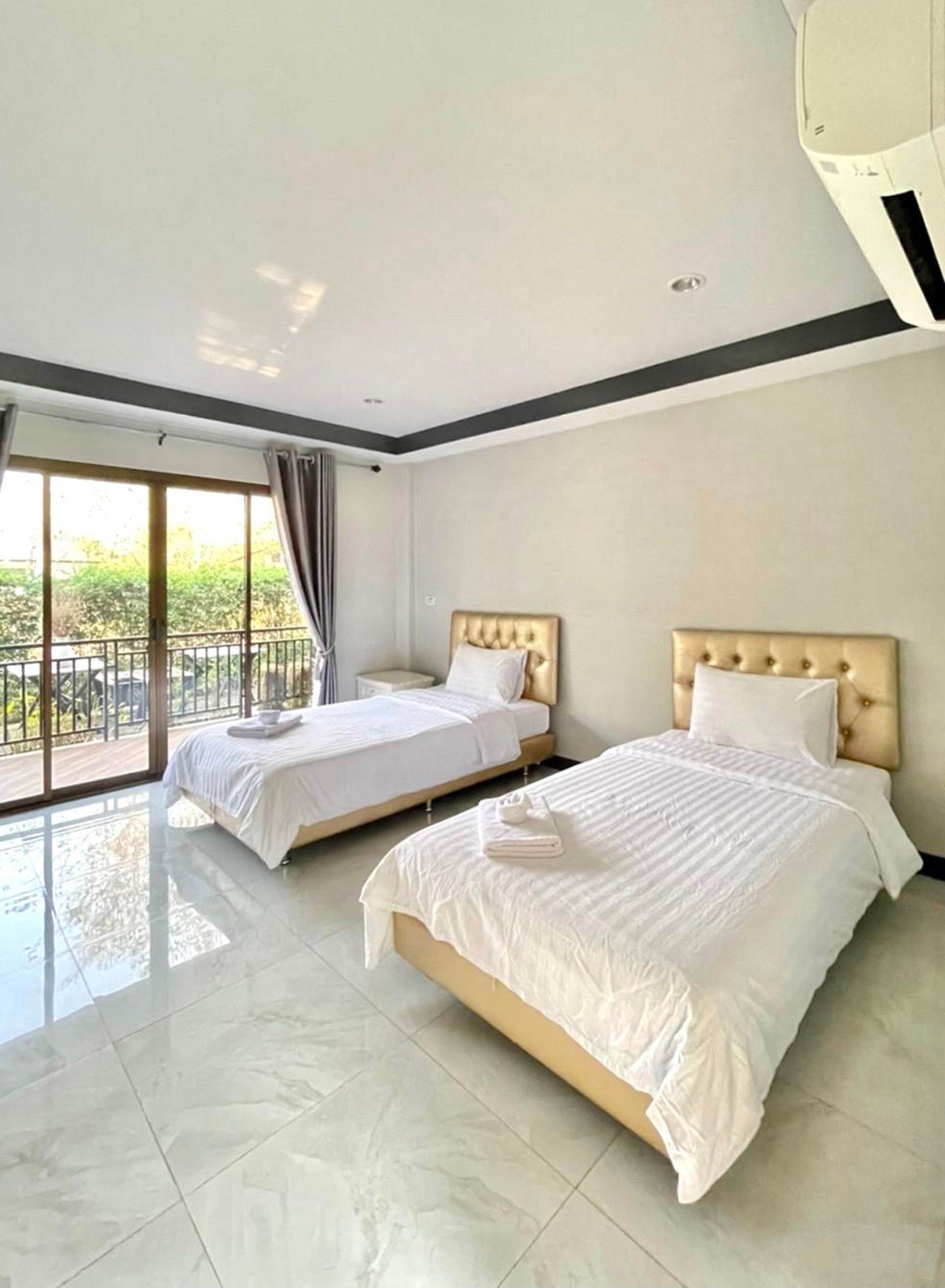 Habitación de hotel con dos camas, balcón y un ventanal grande.