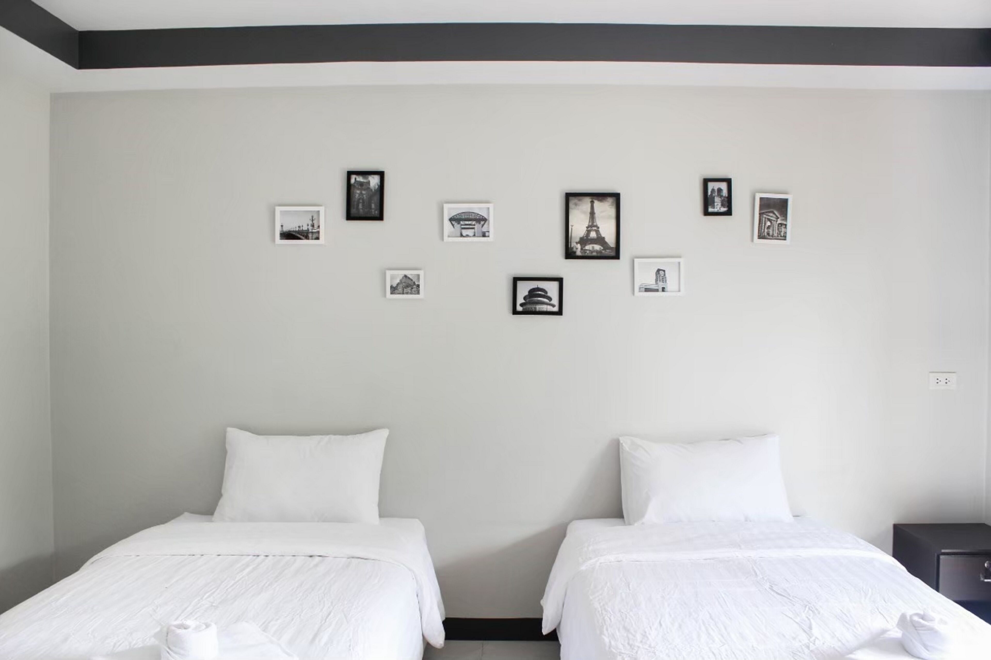 Habitación de hotel con dos camas, un cabecero oscuro y una pared decorada con fotografías blanco y negro.