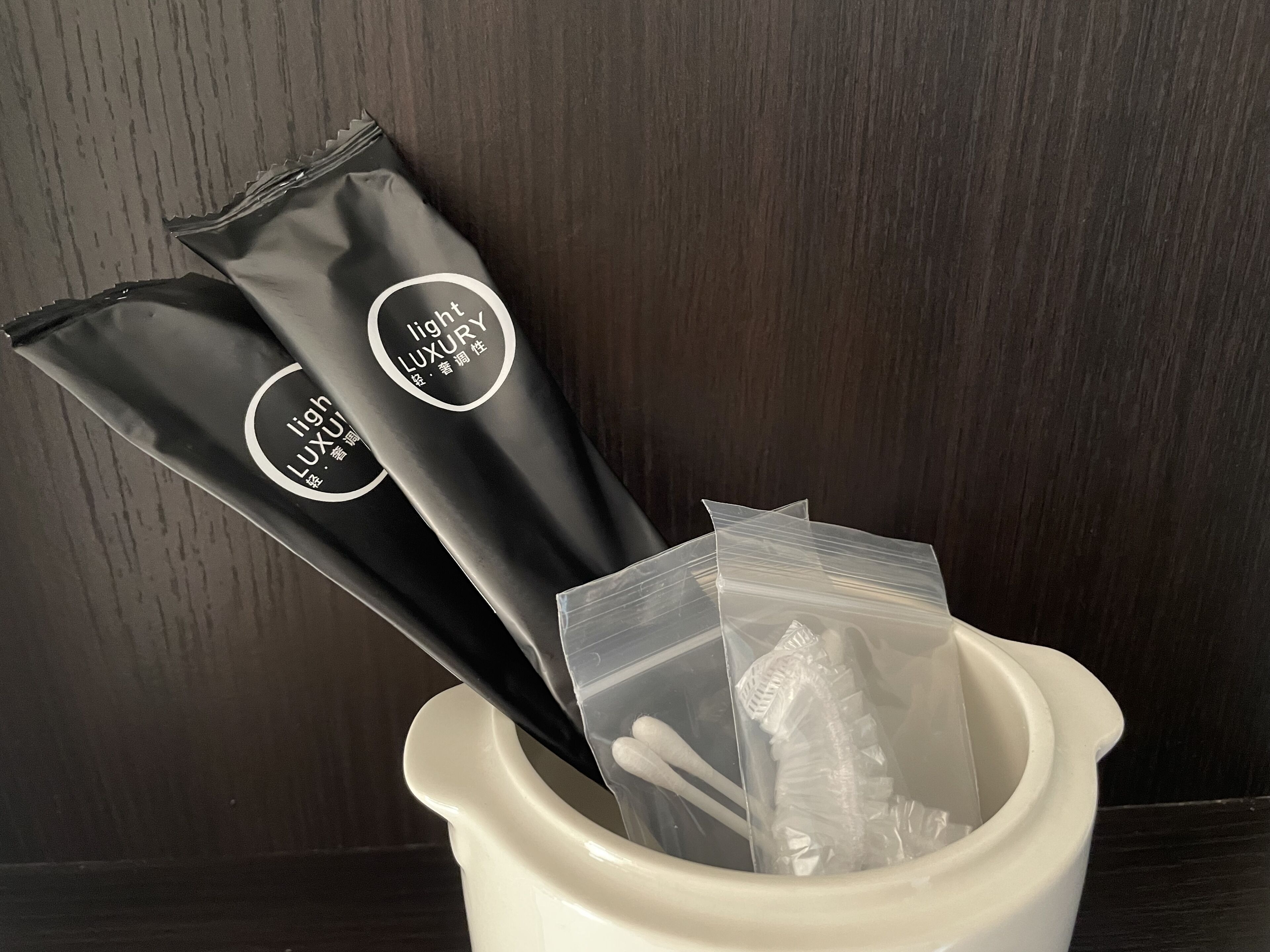 Dos maletas negras con texto blanco y un recipiente de cerámica blanca con una bolsa de plástico transparente y un objeto blanco en su interior.