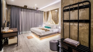 A modern hotel room with a bed, bedside table, and a large window with curtains. - Phi Phi Andaman Legacy Resort (Ko Phi Phi)