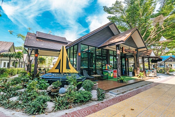 A modern building with a glass facade, outdoor seating area, and a coffee shop named "Coffee a Day". - Phi Phi Andaman Legacy Resort (Ko Phi Phi)