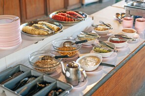 A buffet setup with various food items and utensils. - Phi Phi Andaman Legacy Resort (Ko Phi Phi)