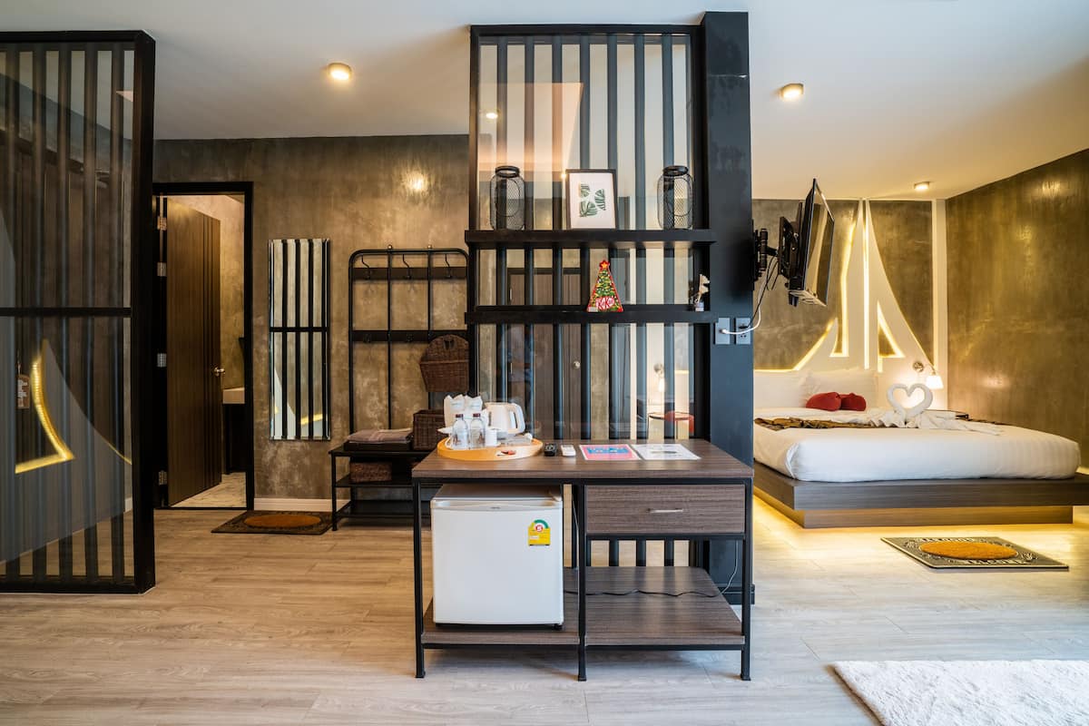 Ein modernes Schlafzimmer mit Bett, Nachttisch und Schreibtisch inklusive Kühlschrank.