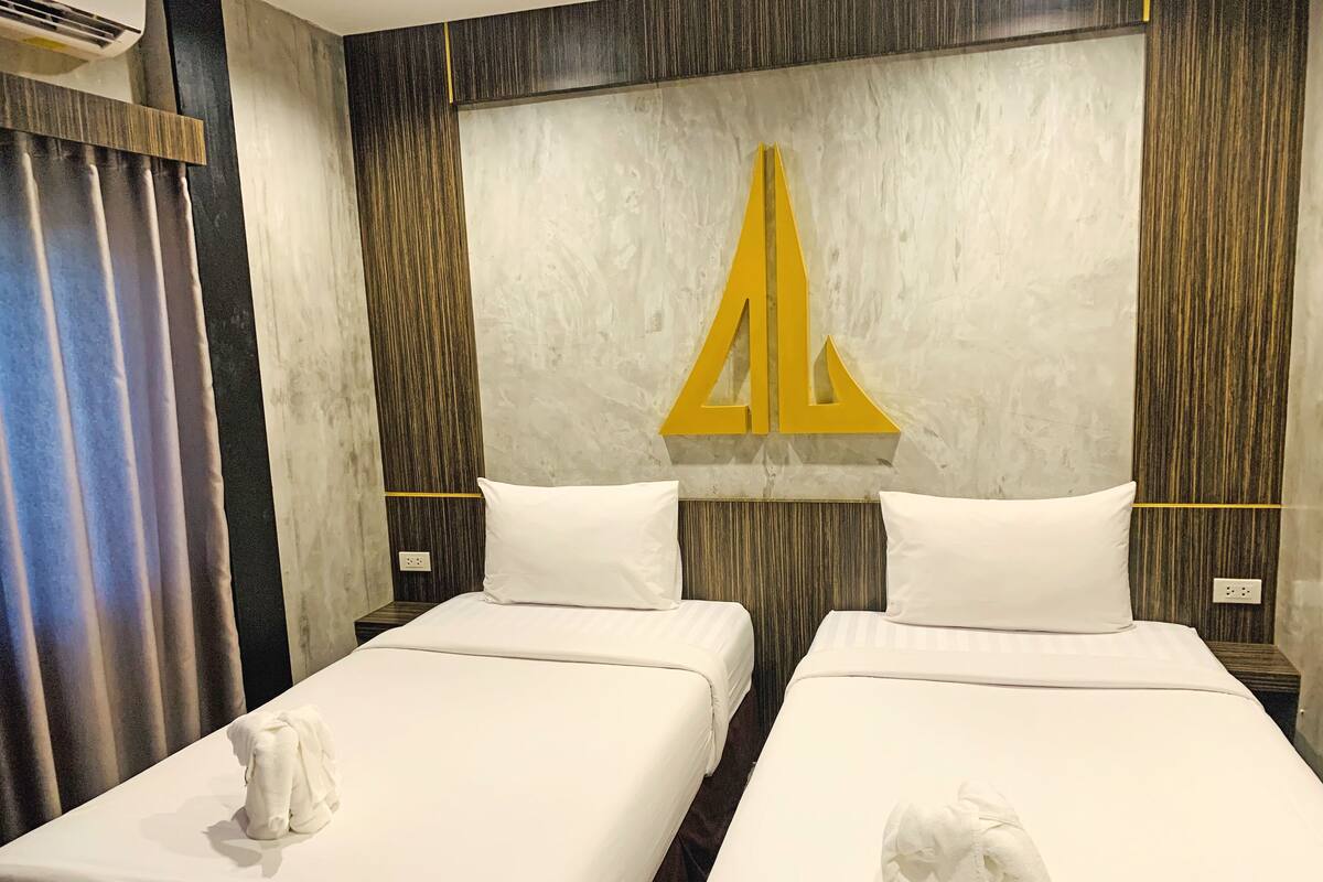 Ein Hotelzimmer mit zwei Betten, jeweils mit weißer Bettdecke und Kissen, sowie einem großen Wandbild.
