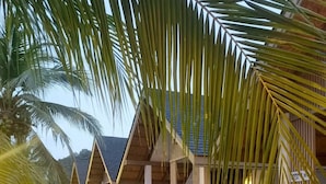 A row of single-story buildings with a sloped roof, surrounded by palm trees. - Phi Phi Andaman Legacy Resort (Ko Phi Phi)