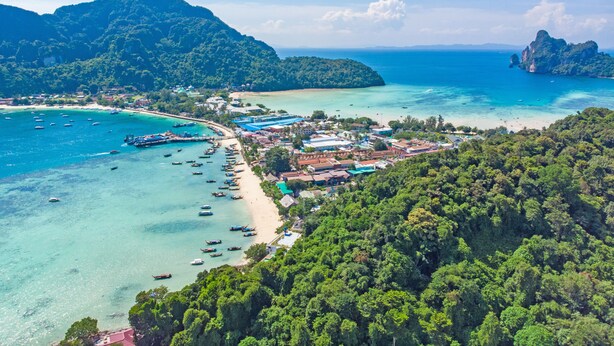 An aerial view of a coastal town with a beach, boats, and lush greenery. - Phi Phi Andaman Legacy Resort (Ko Phi Phi)