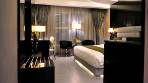 A modern hotel room with a bed, bedside tables, a desk, and a chair. - Frsan Palace Hotel (Manama)