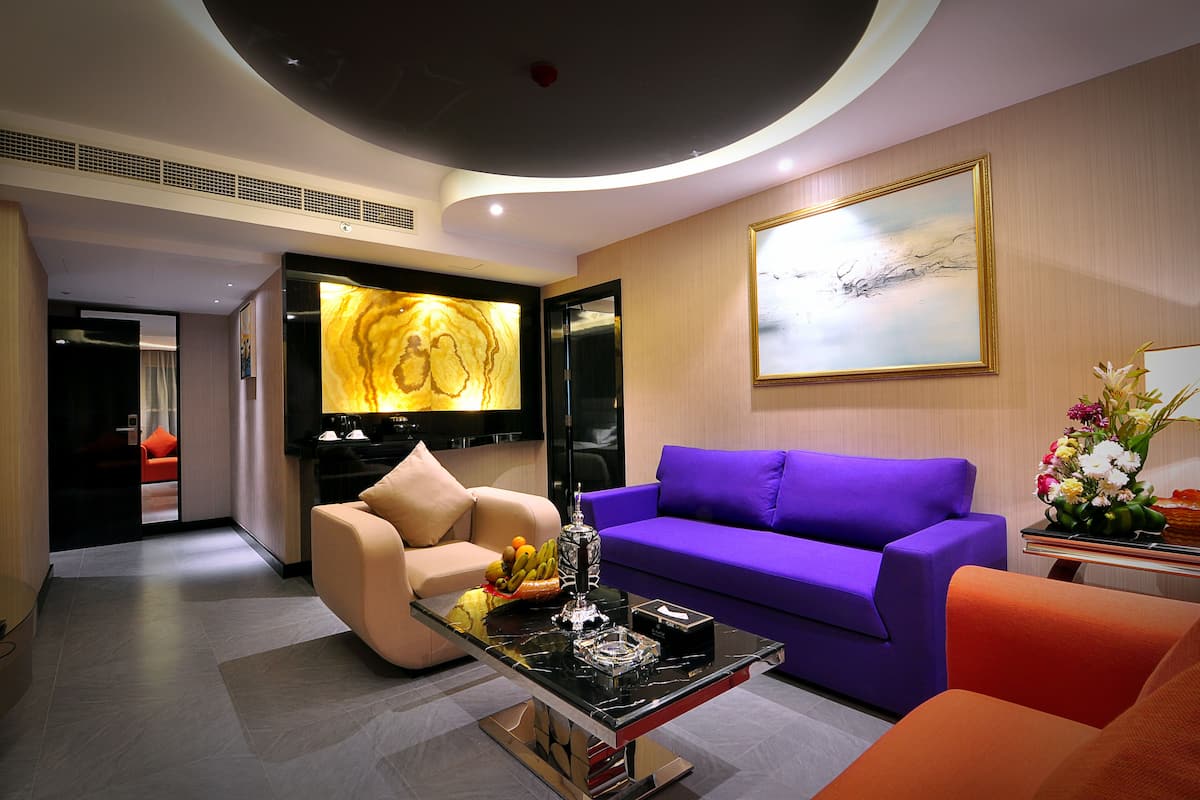 A modern living room with a purple sofa, beige armchair, and a black coffee table.