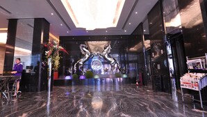 A modern lobby with a reflective marble floor, a reception desk, and a decorative wall with a metallic sculpture. - Frsan Palace Hotel (Manama)