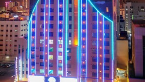 A modern building with a distinctive curved top and illuminated facade. - Frsan Palace Hotel (Manama)