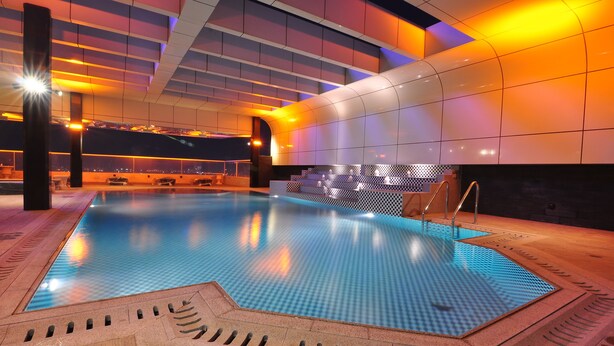 An indoor swimming pool with a tiled floor and a poolside area with a checkered pattern. - Frsan Palace Hotel (Manama)